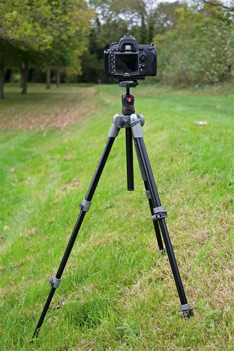 A sturdy tripod with a camera mounted on it, set up in an outdoor location