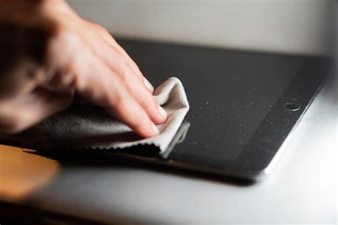a person cleaning a digital drawing tablet screen with a microfiber cloth