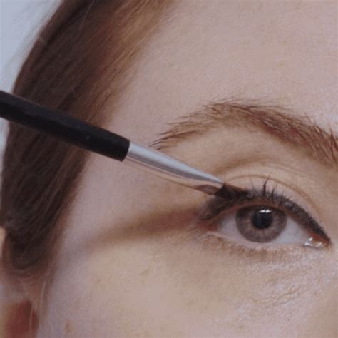 A makeup artist demonstrating winged eyeliner application with a fine-tipped brush