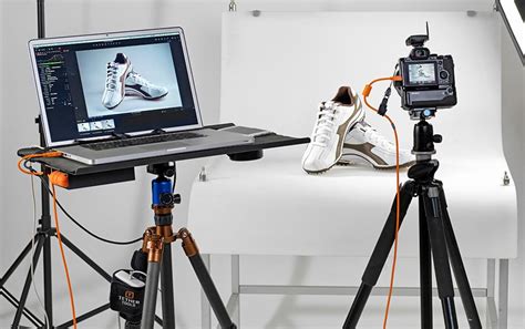 Photographer setting up a tethered shooting rig with a laptop and camera
