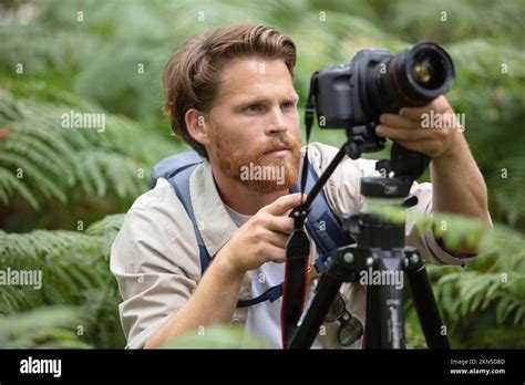 A photographer setting up a camera on a tripod in a field of flowers