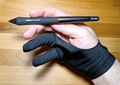 A person wearing a drawing glove and using a stylus on a tablet