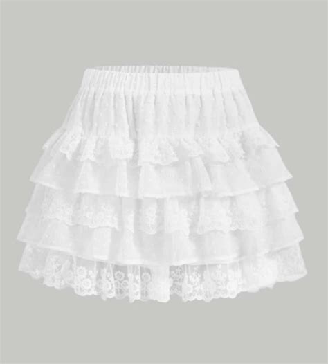 A flat lay of a floral ruffle skirt, a white graphic t-shirt, a denim jacket, and white sneakers.