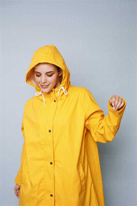 A woman wearing a yellow raincoat, black leggings, and a short floral ruffle skirt with black rain boots.